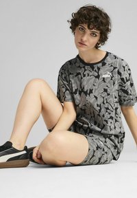 Conjunto de camiseta y pantalones cortos de estampado de camuflaje gris, fabricado en tejido ligero, con cuello redondo y un pequeño logo de PUMA en el pecho.