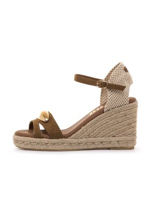 Sandalia de cuña de ante marrón con correa de tela tejida en el tobillo, hebilla ajustable y adorno decorativo en tono dorado en la punta. Plataforma estilo yute.
