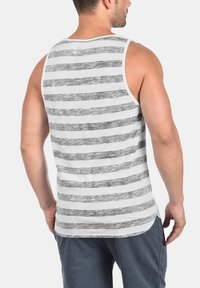 Herre tanktop med grå og hvite horisontale striper. Laget av et mykt, lett stoff med en avslappet passform og buet nederkant.