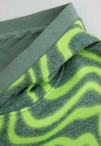 Jasnozielony sweter z teksturowanym, prążkowanym kołnierzem. Tułów prezentuje falisty, limonkowy wzór na marmurkowym szarym tle.