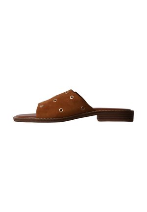 Sandale mule en daim marron avec petits œillets métalliques ronds et petit talon empilé sur fond blanc.