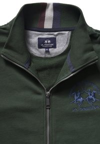 Green zip-up jacket with grey and navy accents, featuring an embroidered polo scene. Made of soft fabric with a high collar and partial zipper.