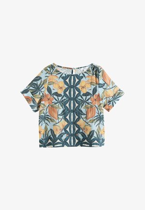 Kortærmet bluse med lyseblå baggrund og symmetrisk tropisk blomsterprint i orange, gule og mørkegrønne nuancer.