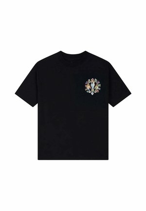 Camiseta negra de manga corta con un pequeño diseño multicolor de llama alrededor de un símbolo central de flor de lis en el pecho izquierdo.