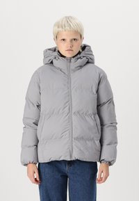 Grå puffjacka med huva, som har en framdragkedja, elastiska ärmslut och fluffig isolering. Bärs med blå jeans. Minimalistisk design.