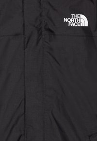 Černá bunda s hladkou texturou, jemnými vertikálními pruhy a logem "The North Face" v bílém na levé horní straně.