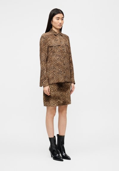 Σετ μπλούζας και φούστας με λεοπάρ μοτίβο, απαλό ύφασμα, μακριά μανίκια, δύο τσέπες μπροστά, συνδυασμένο με μαύρα μποτάκια αστραγάλου με ψηλό τακούνι.