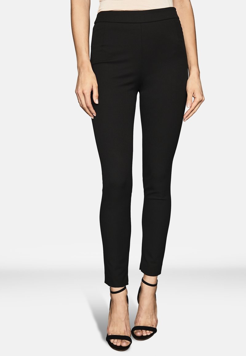 Svarta tajta byxor med en slät textur och hög midja. Har två sidofickor och en kortad fåll, tillsammans med svarta remsandaler.