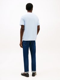 Světle modré tričko s krátkým rukávem a kulatým výstřihem, doplněné tmavě modrými džíny s ohrnutými manžetami a klasickým střihem.