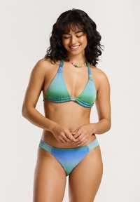 Bikini szett, amely zöldből kékre gradálódó színátmenetet mutat, csillogó textúrával, háromszög alakú melltartóval és alacsony derékú alsó résszel, kontrasztos csíkokkal.