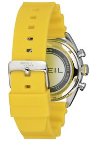 Montre avec bracelet en silicone jaune, boîtier en acier inoxydable, cadran rond et accents argentés, avec un design minimaliste et un cadran clair.