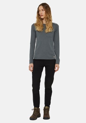 Camisa gris de manga larga con un bolsillo en el pecho, combinada con pantalones negros y botas de senderismo marrones. Presenta un diseño ajustado y una tela texturada.