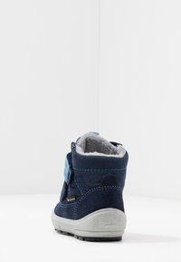Marineblaues Wildlederstiefel mit grauem Kunstfellfutter, blauen Akzenten und Klettverschluss. Gummisohle mit strukturiertem Profil für besseren Halt.