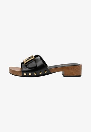 Black leather slide sandal with a gold buckle and decorative studs, resting on a wooden block heel and a black rubber sole.