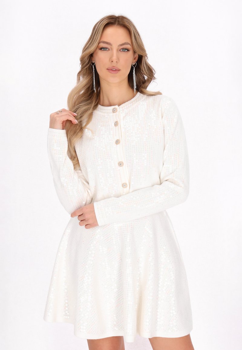 Rochie albă cu mâneci lungi, guler rotund și închidere cu nasturi. Prezintă un model texturat și o fustă evazată.