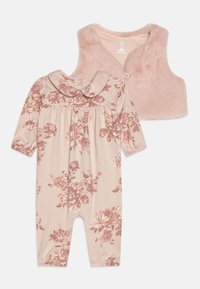 Blommönstrad rosa overall med långa ärmar och krage, tillsammans med en mjuk rosa faux fur-väst med knäppning fram.