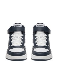 Kotníkové tenisky s barevným schématem v námořnické modři a bílé, vyrobené z kůže, s hustými bílými tkaničkami a suchým zipem pro pevné uchycení.