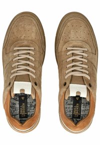 Béžové nubukové tenisky s perforovanými detaily, krémovými šňůrkami, hnědými akcenty a vzorovanou stélkou se značkovým logem na bílém štítku.