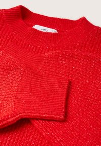 Pull en maille rouge avec col rond et poignets côtelés, montrant un gros plan de la texture et du tissage du tissu.