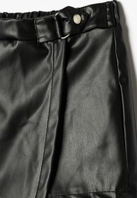 Zwarte leren rok met een gladde textuur, elastische tailleband en een zijsluiting met een metalen knoop en D-ring detail.