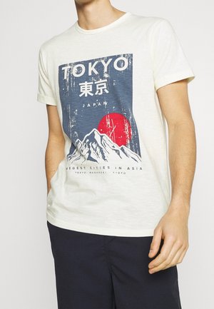 T-shirt en coton couleur crème présentant un design graphique avec des montagnes, un soleil rouge, et le texte "Tokyo Japan" en impression vieillie.