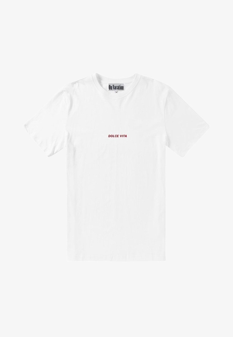 T-shirt blanc à manches courtes et col rond avec un petit texte rouge "DOLCE VITA" centré sur la poitrine et une étiquette indiquant "On Vacation" à l'intérieur du col.