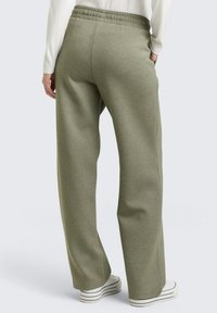 Groene, ontspannen zittende joggingbroek met een elastische tailleband. Gemaakt van zacht materiaal, met zijnaden en een rechte pijp.