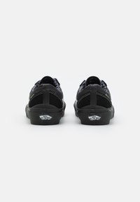 Svarta canvas-sneakers med låg design, prydda med en texturerad mockadetalj och vit sömnad. Inkluderar en klassisk logotyp på hälen.