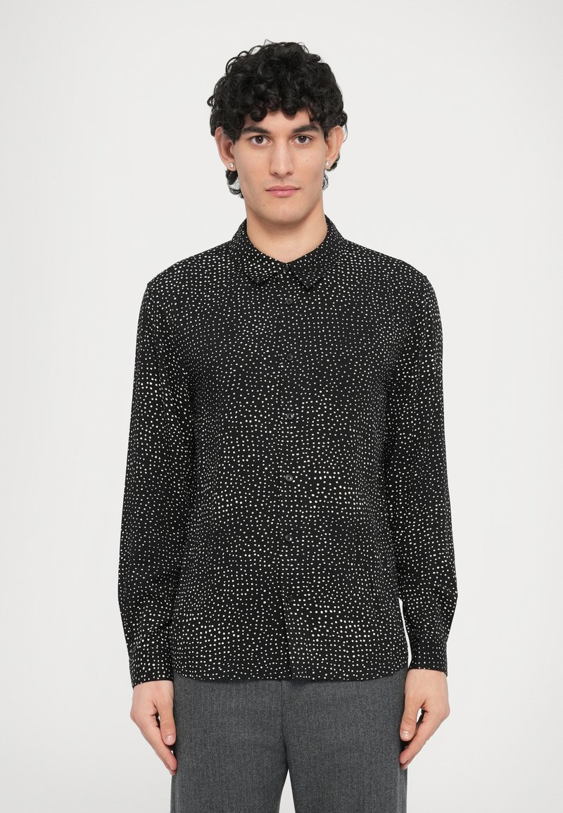 Schwarzes Langarmhemd mit kleinem weißen Tupfenmuster, Kragen und Knopfverschluss, hergestellt aus leichtem Stoff.