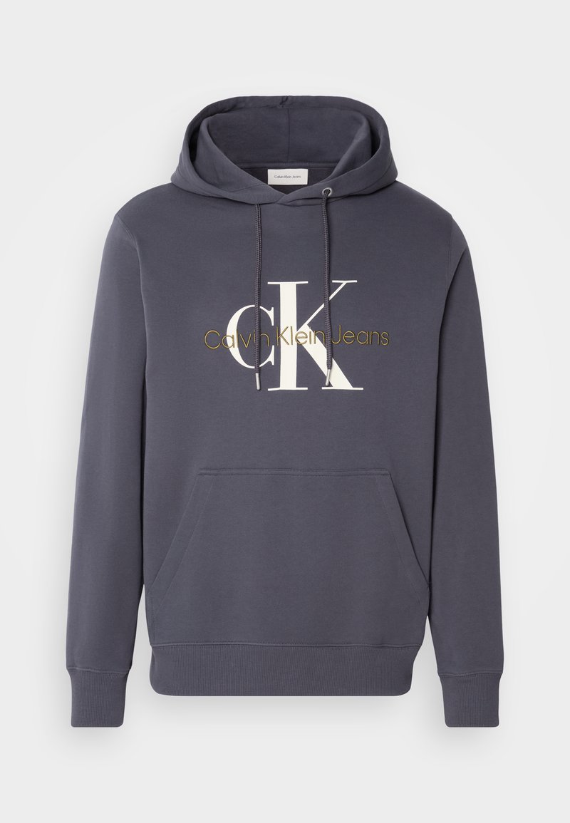 Sudadera con capucha en gris oscuro con un bolsillo tipo canguro en el frente. Presenta un grande logo blanco de "CK" y el texto en dorado "Calvin Klein Jeans".