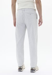 Pantalons rayés gris clair avec une taille élastique, deux poches arrière et une coupe décontractée. Assortis à des baskets décontractées.