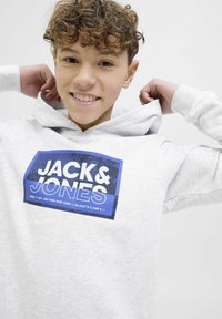 Felpa grigia chiara realizzata in morbido materiale, con un logo rettangolare blu contenente il testo "JACK & JONES". Dotata di tasca a marsupio frontale.