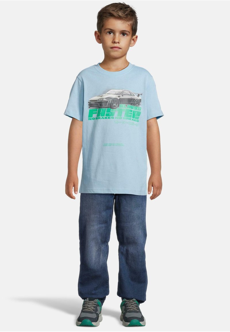 Lyseblå bomulls t-skjorte med grafisk print av en bil og tekst. Kombinert med mørkeblue denim jeans og grå sneakers med grønne detaljer.