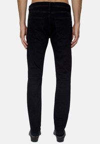 Jeans de mezclilla negra con corte ajustado, que cuentan con dos bolsillos traseros y detalles de costura sutiles, mostrados desde la vista posterior.