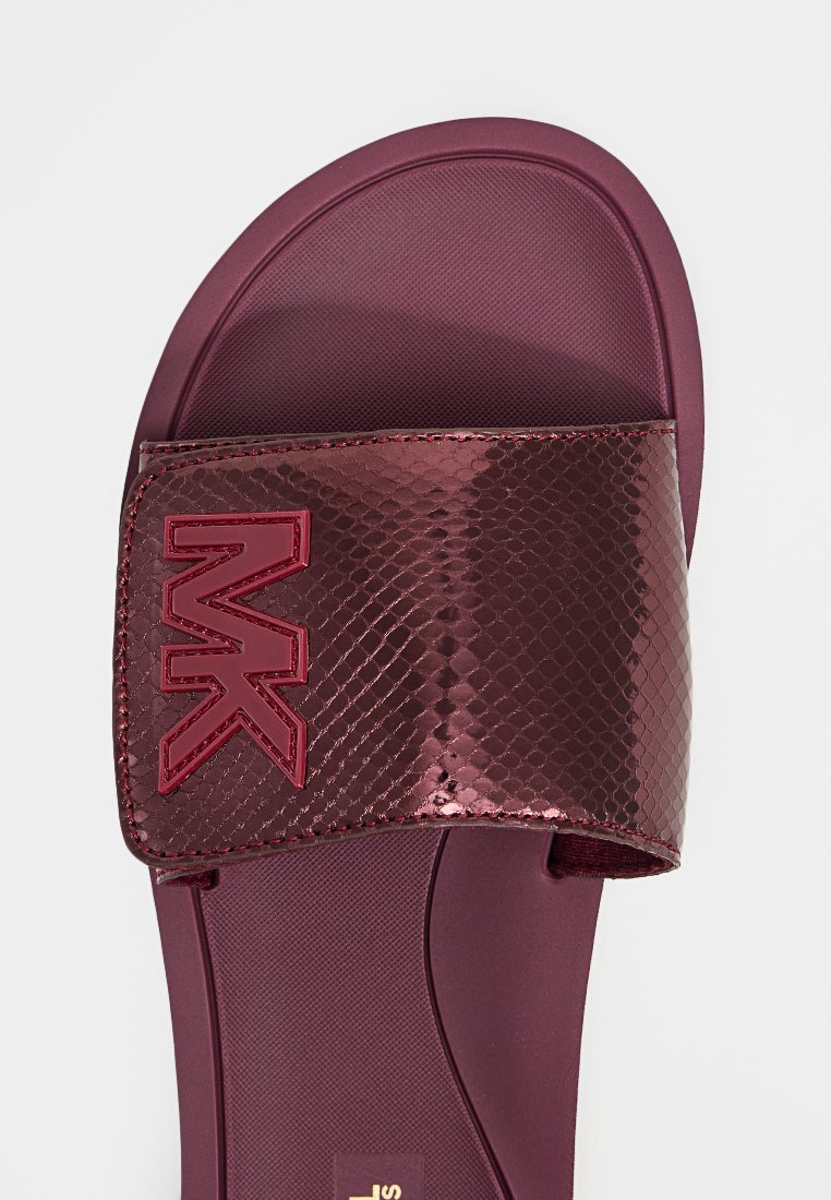 Bordowe sandały z błyszczącym, teksturowanym paskiem z wytłoczonym logo. Wkładka jest gładka o nieco konturowanym kształcie.
