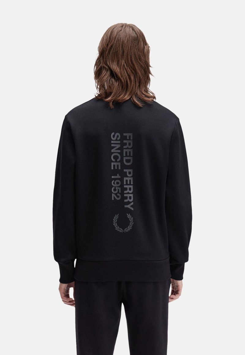 Felpa nera con bordo e polsini a coste. Sul retro è stampato in grande testo a contrasto "FRED PERRY SINCE 1952" con un simbolo di alloro.
