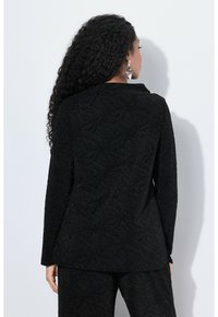 Černá texturovaná bunda s vzorovaným designem, dlouhými rukávy a límcem. Tkanina je zdobená třpytivými akcenty, které dodávají detail.