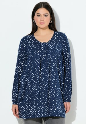 Tunique bleu marine à manches longues, avec un col rond et des motifs de cœurs blancs. Fabrication en tissu doux et flexible avec une coupe ample.