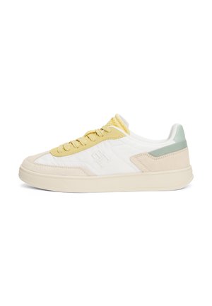 Niski sneaker z białą cholewką, żółtymi sznurowadłami i lamówką, beżowymi akcentami z zamszu, jasnozieloną pętelką na pięcie oraz tłoczonym logo "H" po boku.