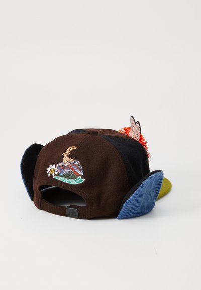Mütze mit einem braunen Filzkörper, besticktem Design mit einer Bergszene, blauen Cord-Seitenpaneelen und einem grünen Schild. Enthält bunte Akzente.