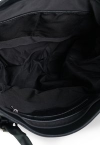 Zwarte stoffen tas interieur met een gladde textuur, voorzien van compartimenten en zakken voor organisatie. Ritssluiting langs de bovenrand.