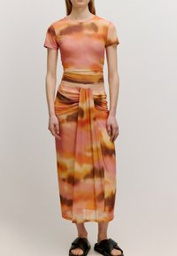 Zweiteiliges Outfit aus weichem, leichtem Stoff mit einem orange-rosa Batikmuster. Besteht aus einem figurbetonten Kurzarmoberteil und einem drapierten Rock.