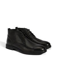 Bottines en cuir noir avec une finition texturée, semelles en caoutchouc plates et un design classique à lacets. Présente une pointe lisse et une forme arrondie.