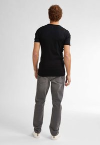 Tricou negru cu mânecă scurtă, blugi de denim gri și adidași de culoare deschisă. Stil casual cu o textură netedă și fără logo-uri vizibile.