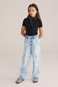 Černý krátký top s krátkým rukávem, světle modré volné cargo džíny s kapsami a černo-šedé vzorované slip-on boty. Jednoduchý design a pohodlný střih.