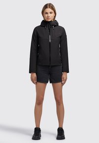 Black, lightweight jacket with a hood, featuring a front zipper and two zippered chest pockets. Paired with denim shorts and black sneakers.