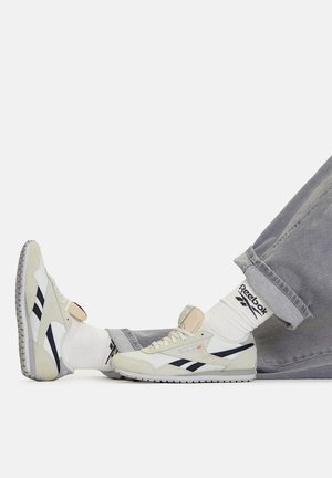 Tennised, mille ülemine osa on helehallist seemisnahast ja võrgust, valgete detailide ja tumelillade külgtriipudega. Omavad paelu ja polsterdatud keelt.