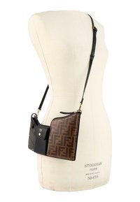Sac bandoulière Fendi marron et noir avec bandoulière ajustable, présenté sur un buste de mannequin couleur crème.
