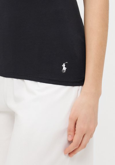 Black cotton T-shirt with a crew neck, short sleeves, and a white embroidered logo at the hem. Paired with white pants.