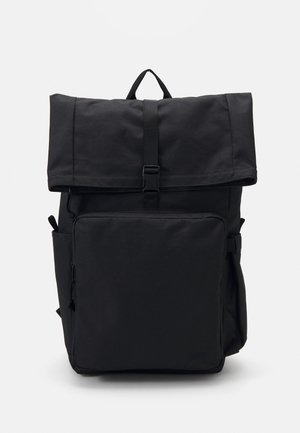 Sac à dos noir à rabat enroulable avec poche avant zippée, poches latérales et fermeture à boucle sur fond blanc.